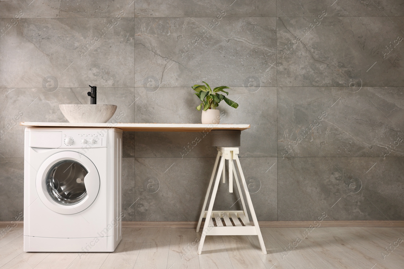 Photo of Stylish laundry room with modern washing machine, space for text. Interior design