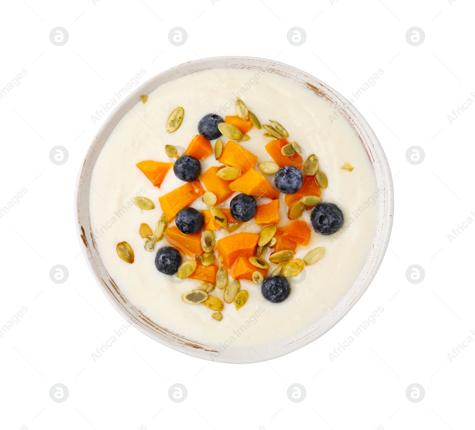 Photo of Bowl of delicious semolina pudding with blueberries, pumpkin and seeds isolated on white, top view