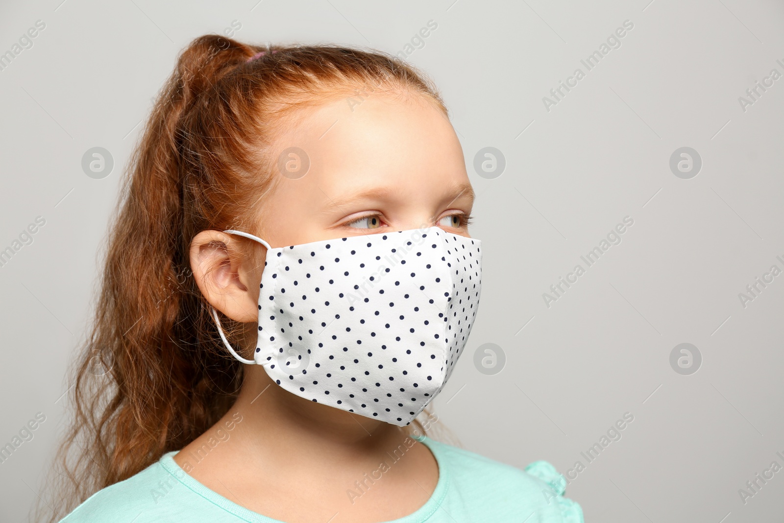 Photo of Preteen girl in protective face mask on light grey background