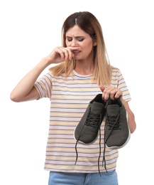 Woman feeling bad smell from shoes on white background. Air freshener