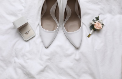 Photo of Flat lay composition with wedding high heel shoes on white fabric, space for text