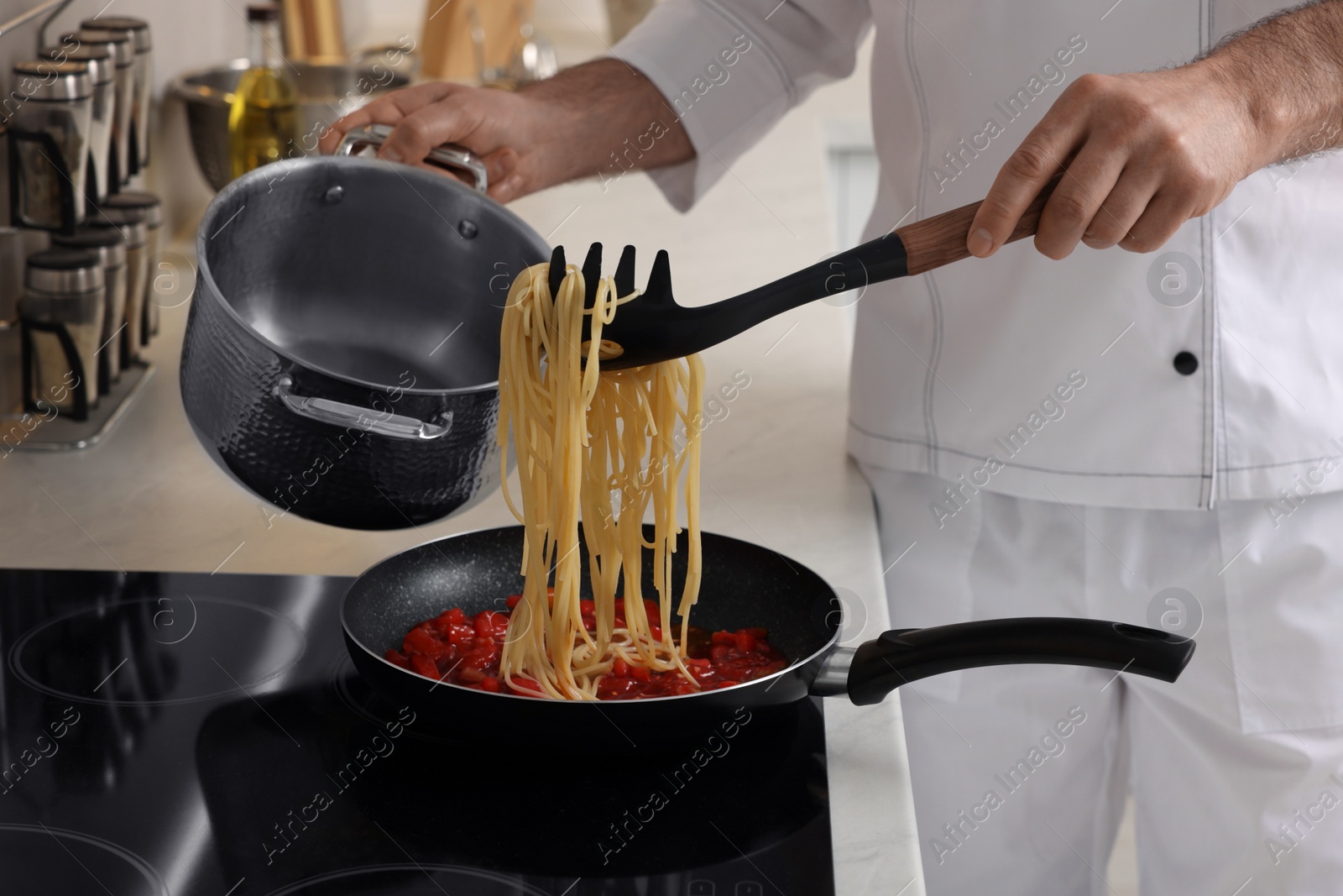 Photo of Professional chef cooking delicious pasta on stove in kitchen, closeup