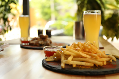Photo of Delicious hot french fries with red sauce served on table