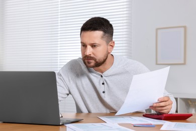 Photo of Man doing taxes at table in room