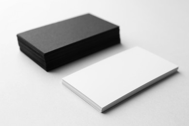 Photo of Blank black and white business cards on light background, closeup. Mockup for design