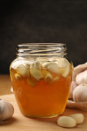 Photo of Honey with garlic in glass jar on wooden table