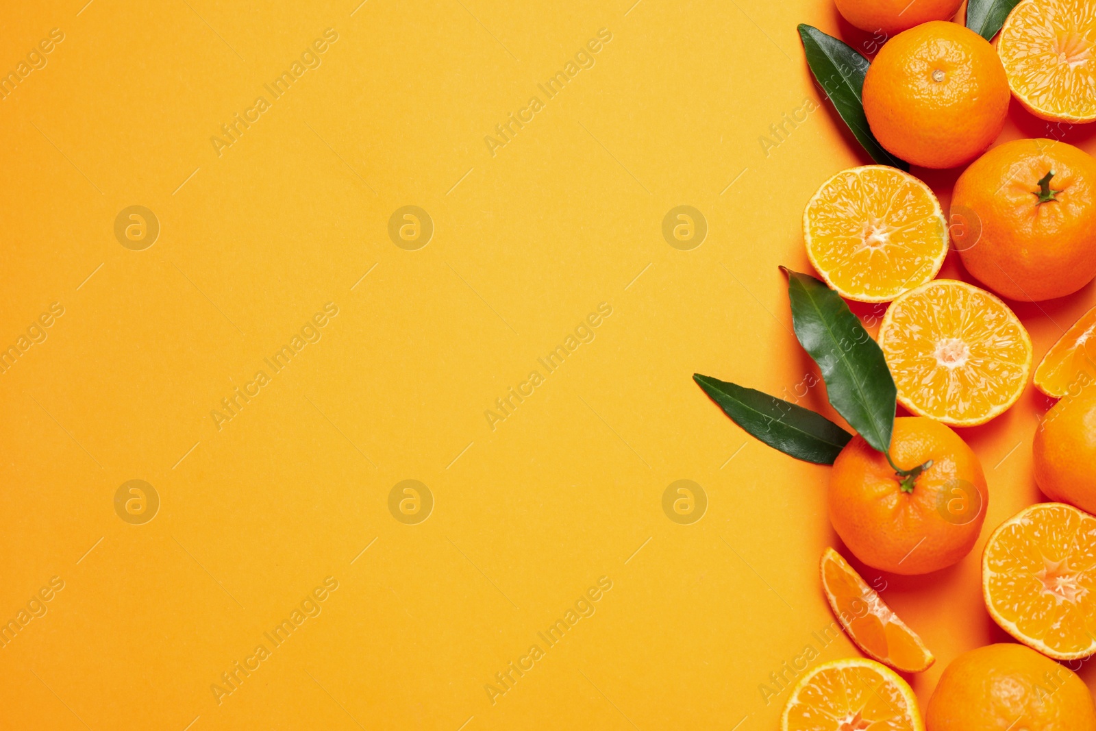 Photo of Flat lay composition with fresh ripe tangerines and space for text on orange background. Citrus fruit