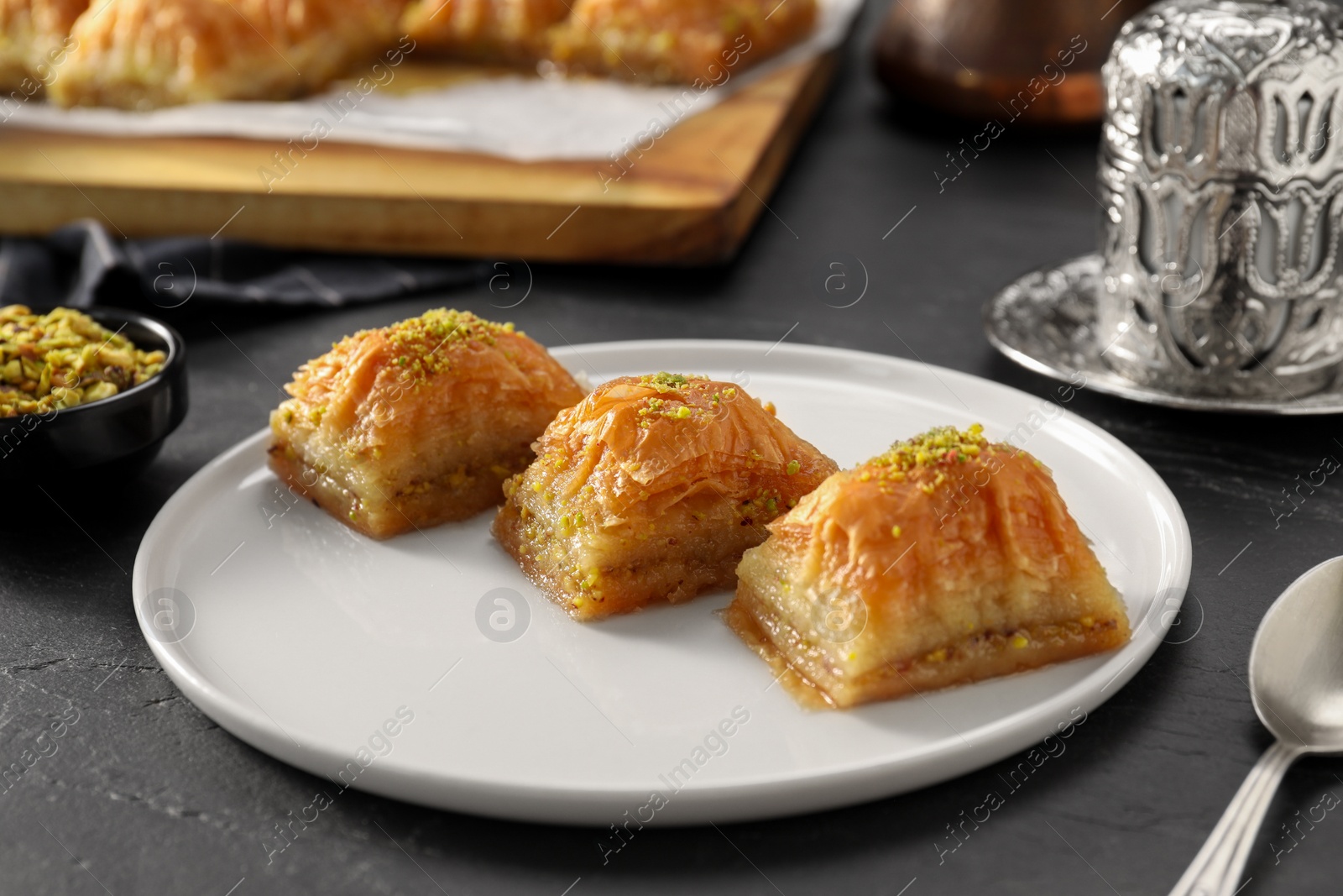 Photo of Delicious sweet baklava with pistachios on black table, closeup