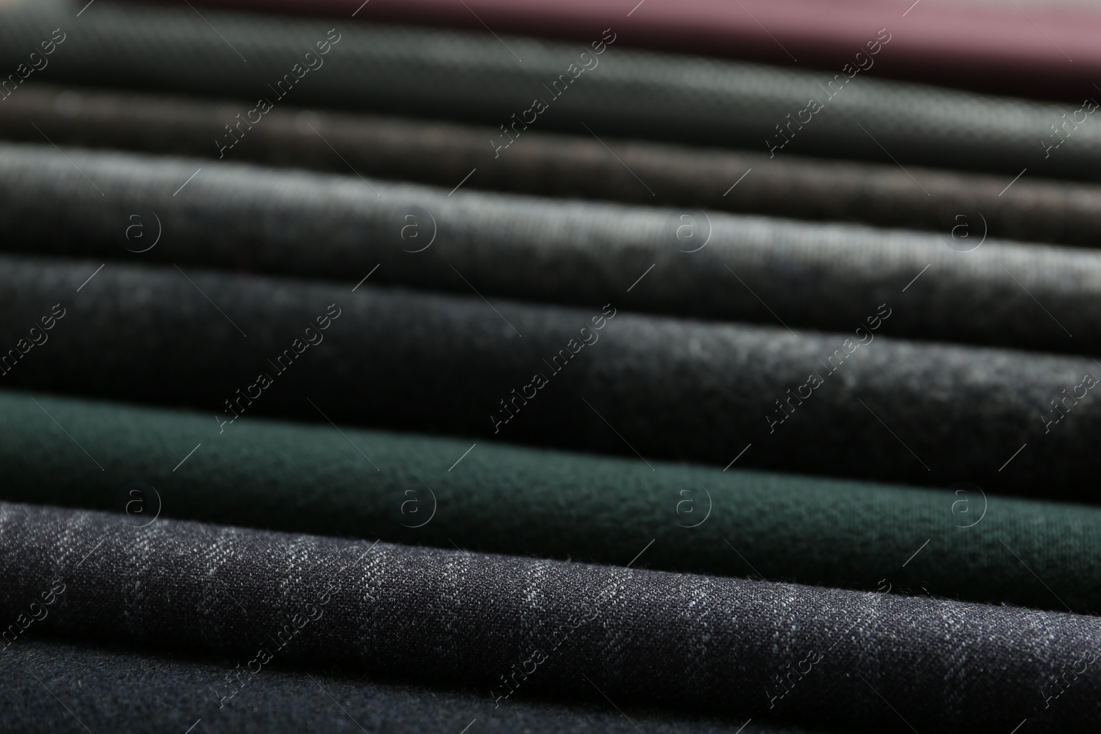 Photo of Stack of different fabric samples as background, closeup. Textile texture