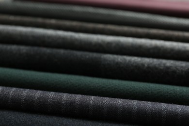 Stack of different fabric samples as background, closeup. Textile texture