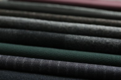 Photo of Stack of different fabric samples as background, closeup. Textile texture