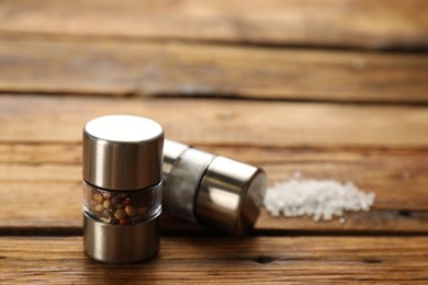 Photo of Salt and pepper shakers on wooden table, closeup