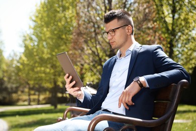 Photo of Man working with tablet on bench in park