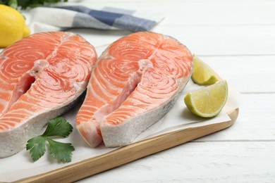 Photo of Fresh raw salmon with parsley and lime on white wooden table. Fish delicacy
