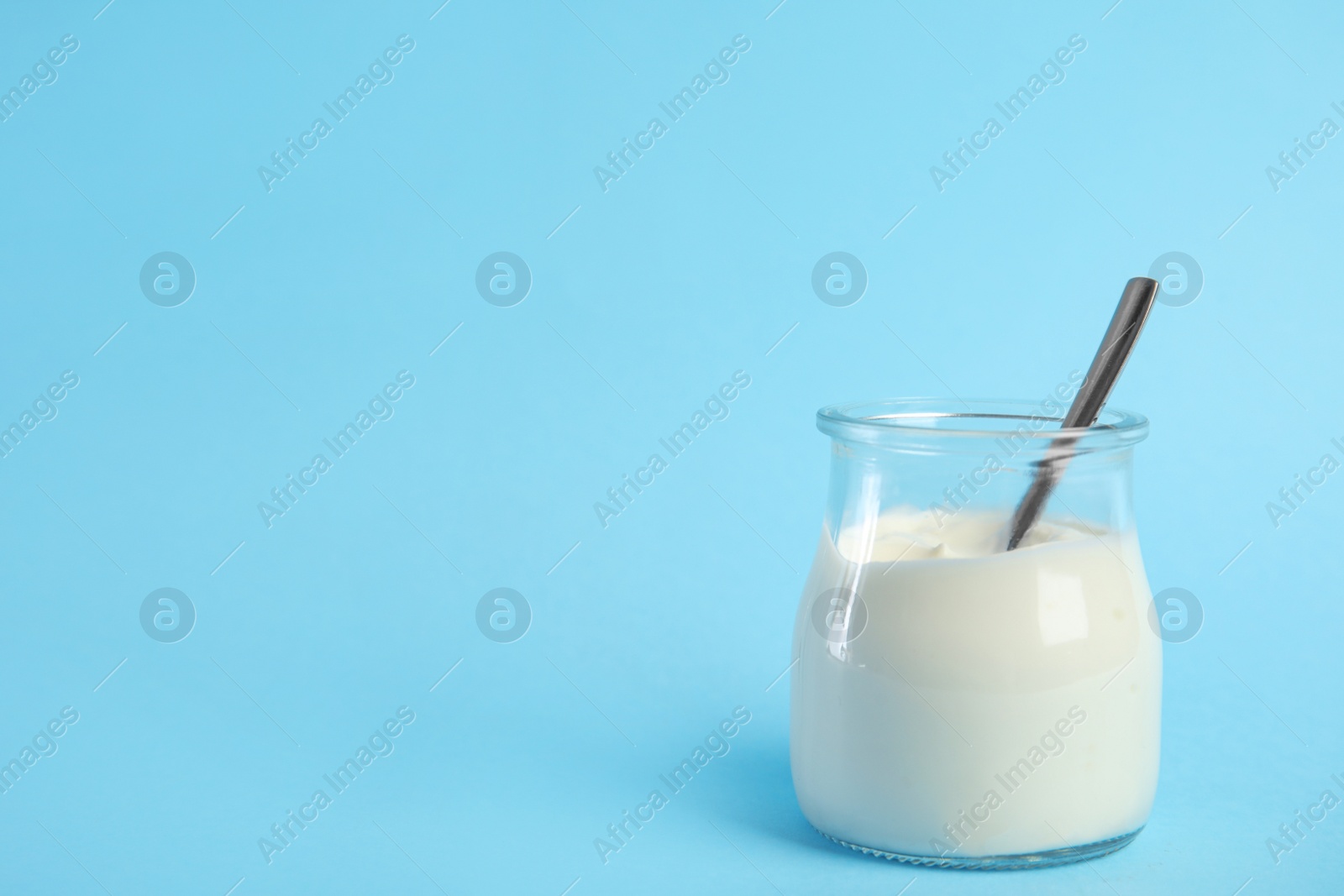 Photo of Tasty organic yogurt on light blue background. Space for text