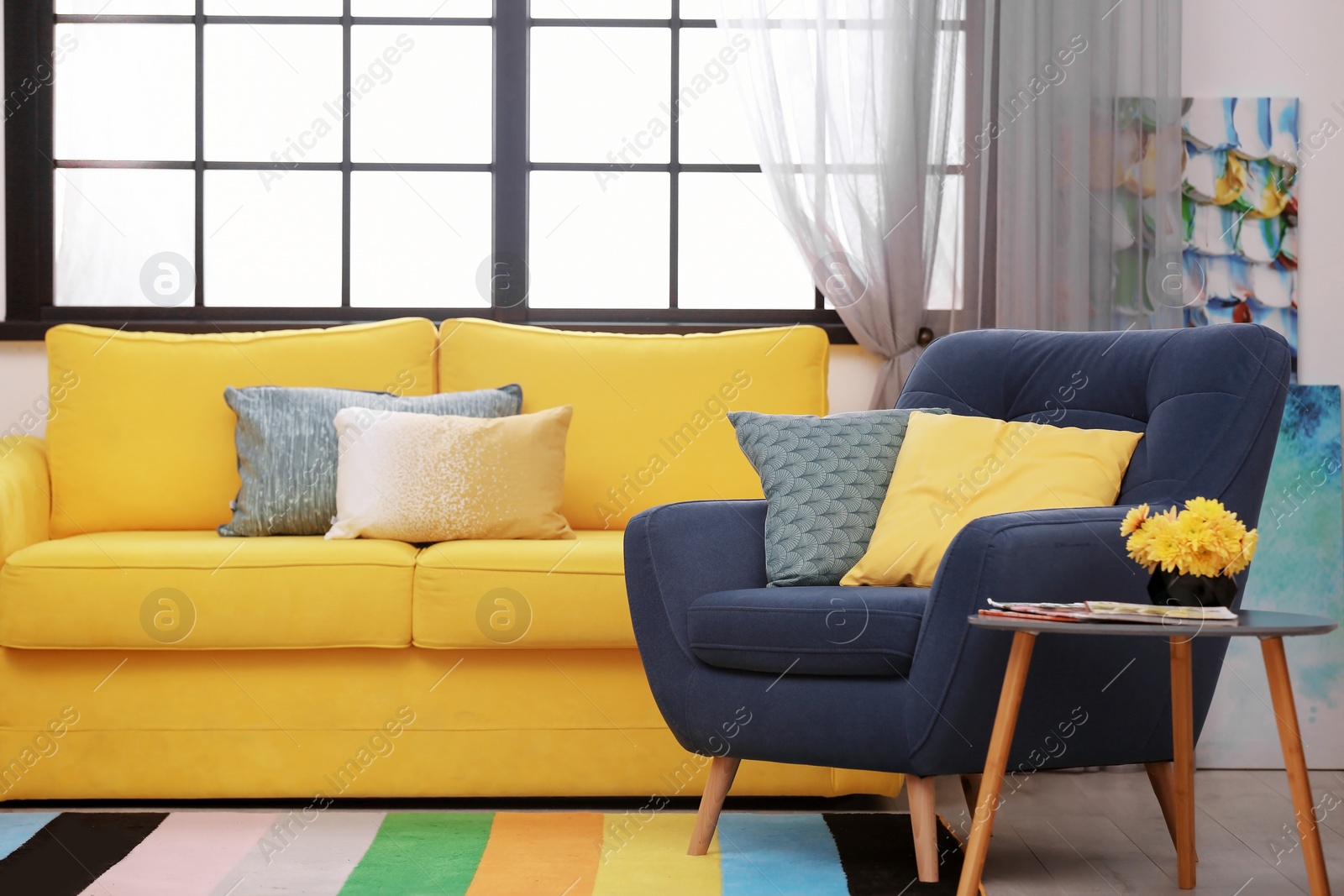 Photo of Modern room interior with comfortable sofa and rainbow carpet