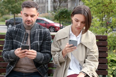 Photo of Couple preferring smartphones over spending time with each other outdoors. Relationship problems