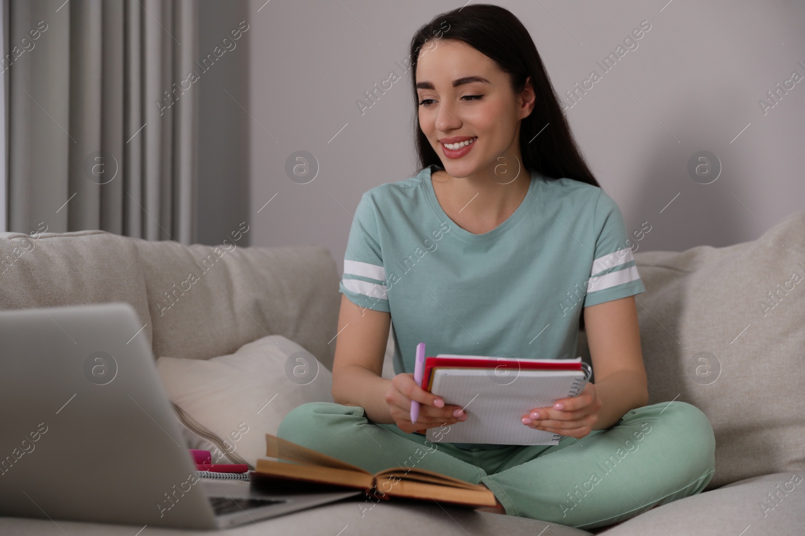 Photo of Young woman watching webinar on sofa at home