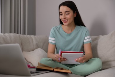 Young woman watching webinar on sofa at home