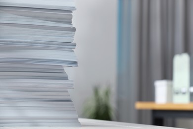 Stack of paper sheets on table against blurred background, closeup. Space for text