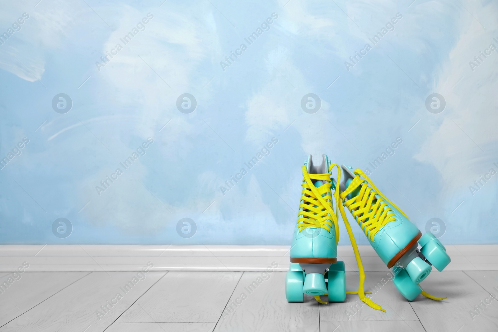 Photo of Vintage roller skates on floor near color wall. Space for text