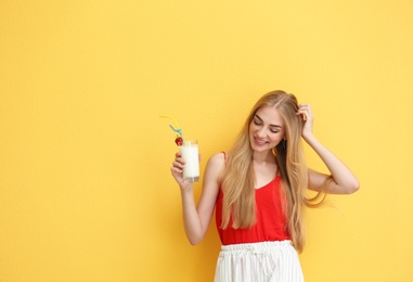 Young woman with glass of delicious milk shake on color background