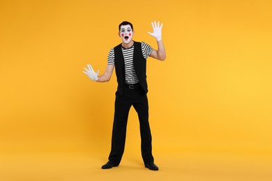 Mime artist making shocked face on orange background