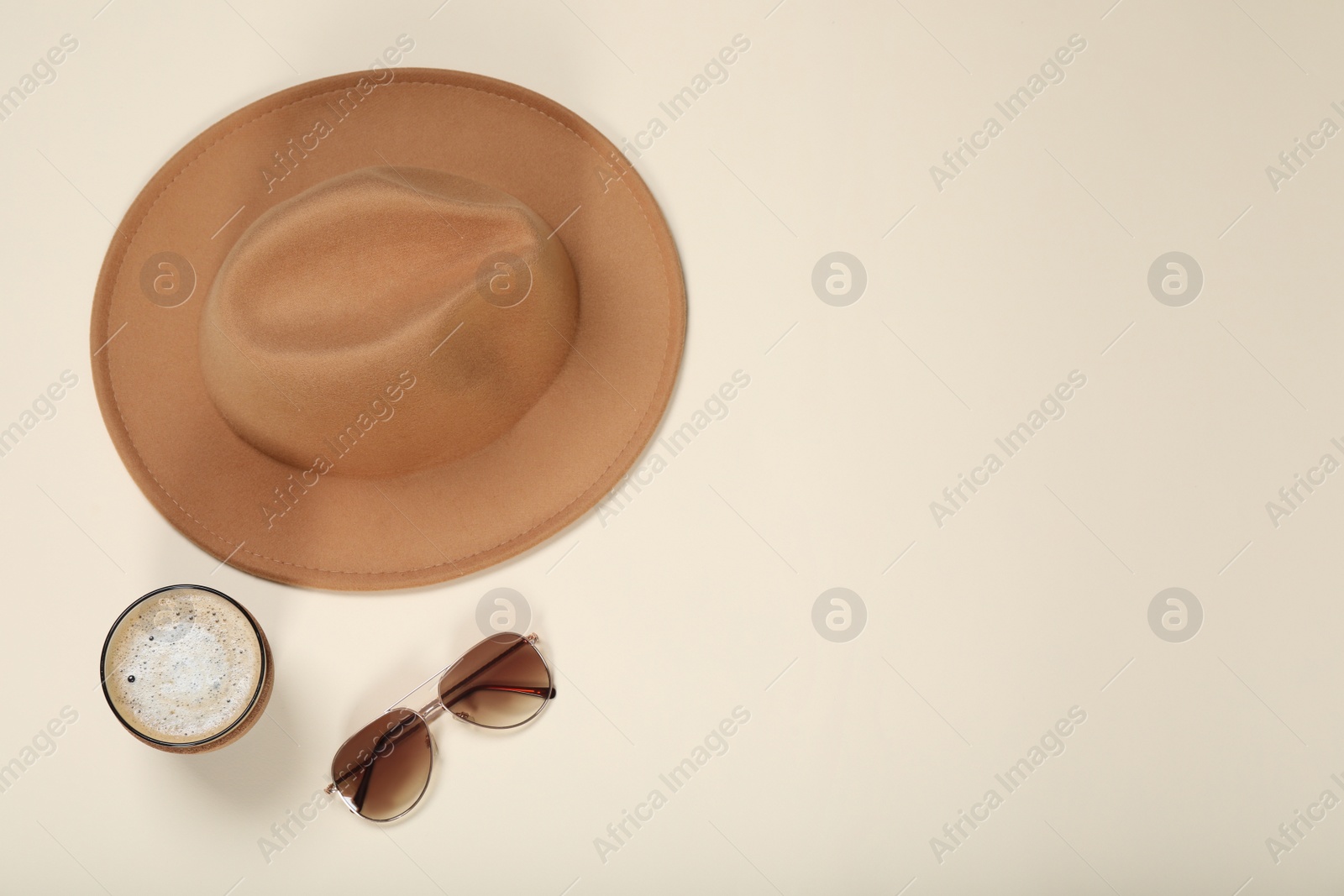 Photo of Stylish hat, sunglasses and coffee on beige background, flat lay. Space for text