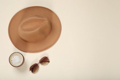 Photo of Stylish hat, sunglasses and coffee on beige background, flat lay. Space for text