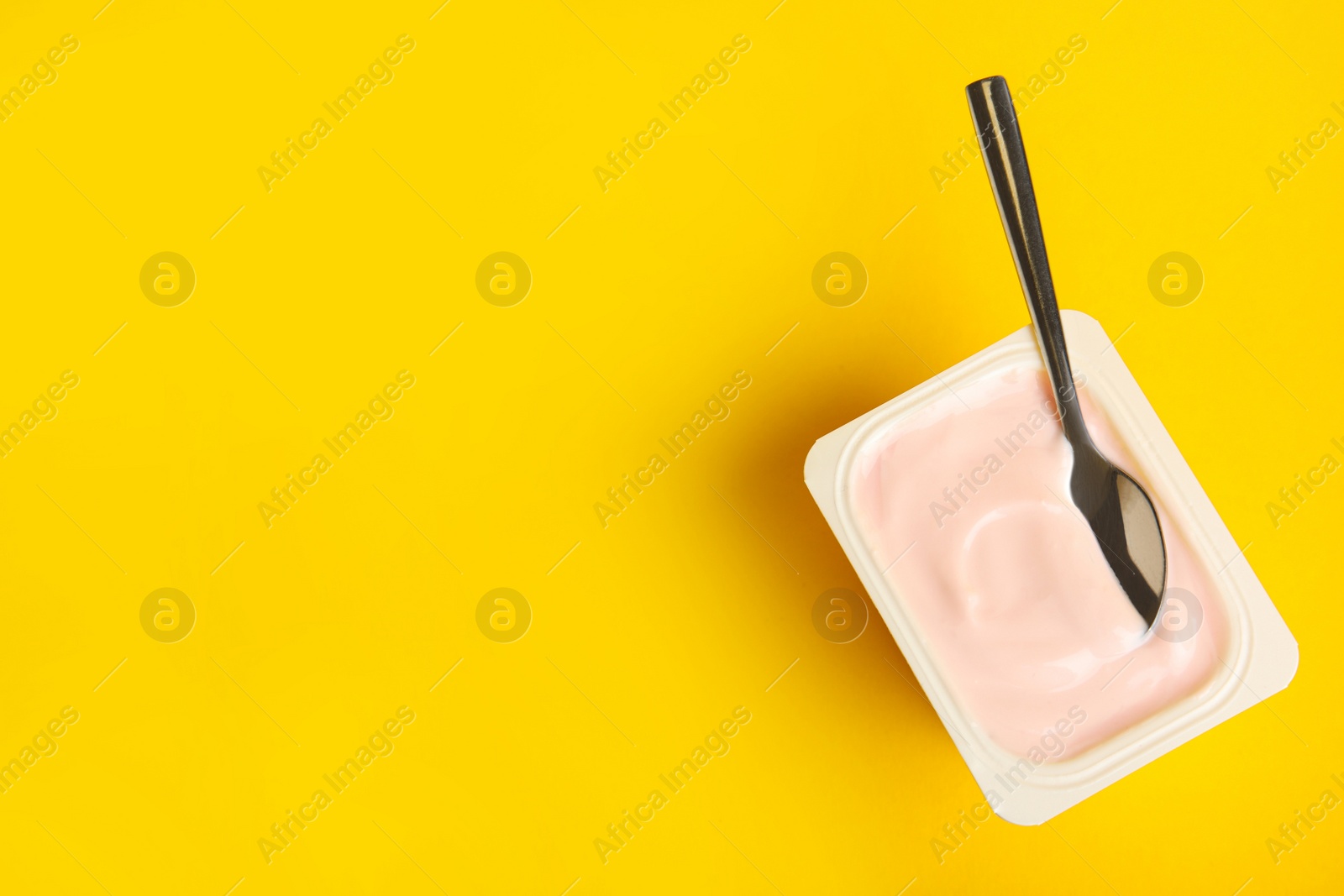 Photo of Tasty organic yogurt on yellow background, top view. Space for text