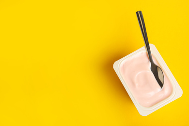 Photo of Tasty organic yogurt on yellow background, top view. Space for text