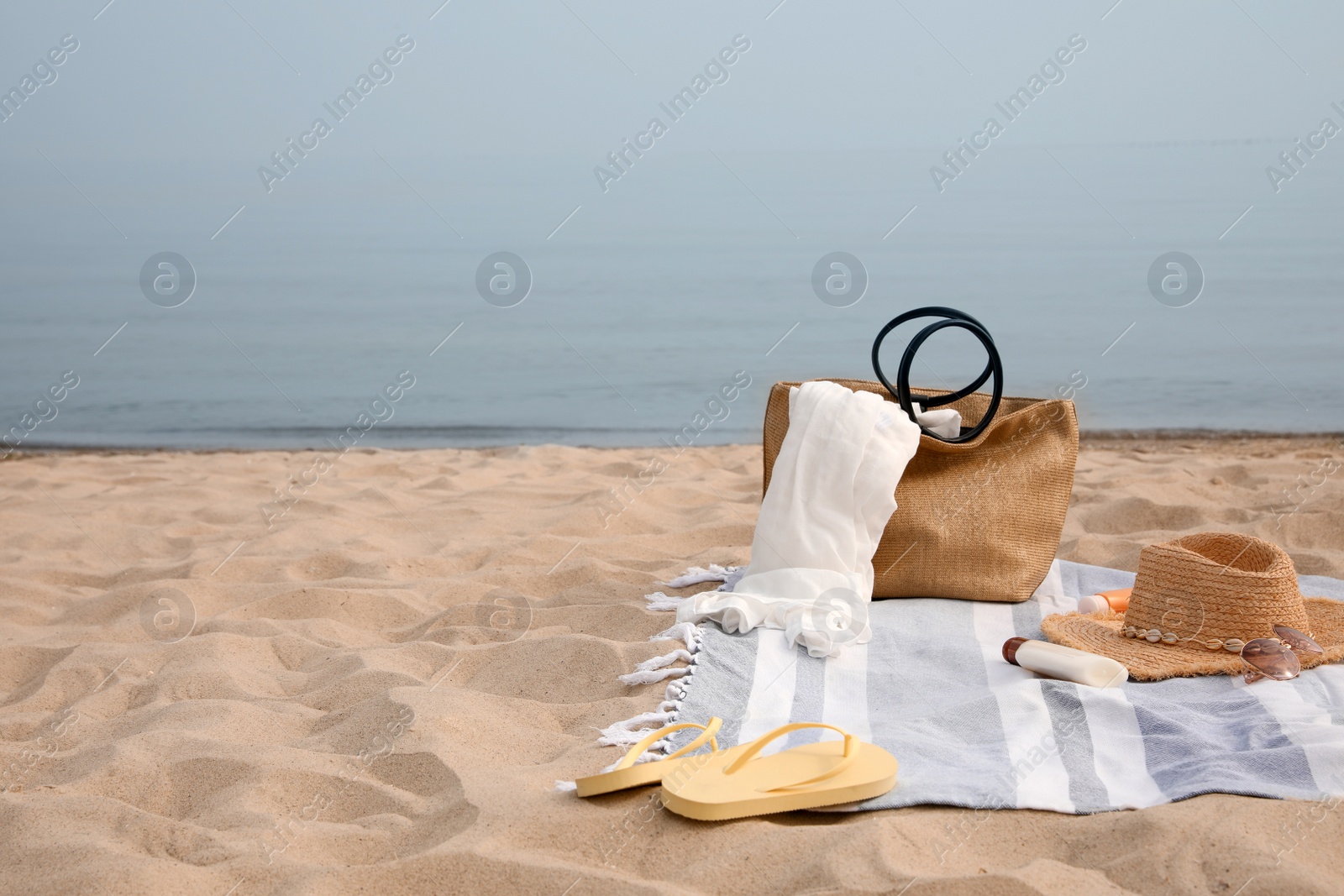 Photo of Bag and other beach items on sandy seashore, space for text