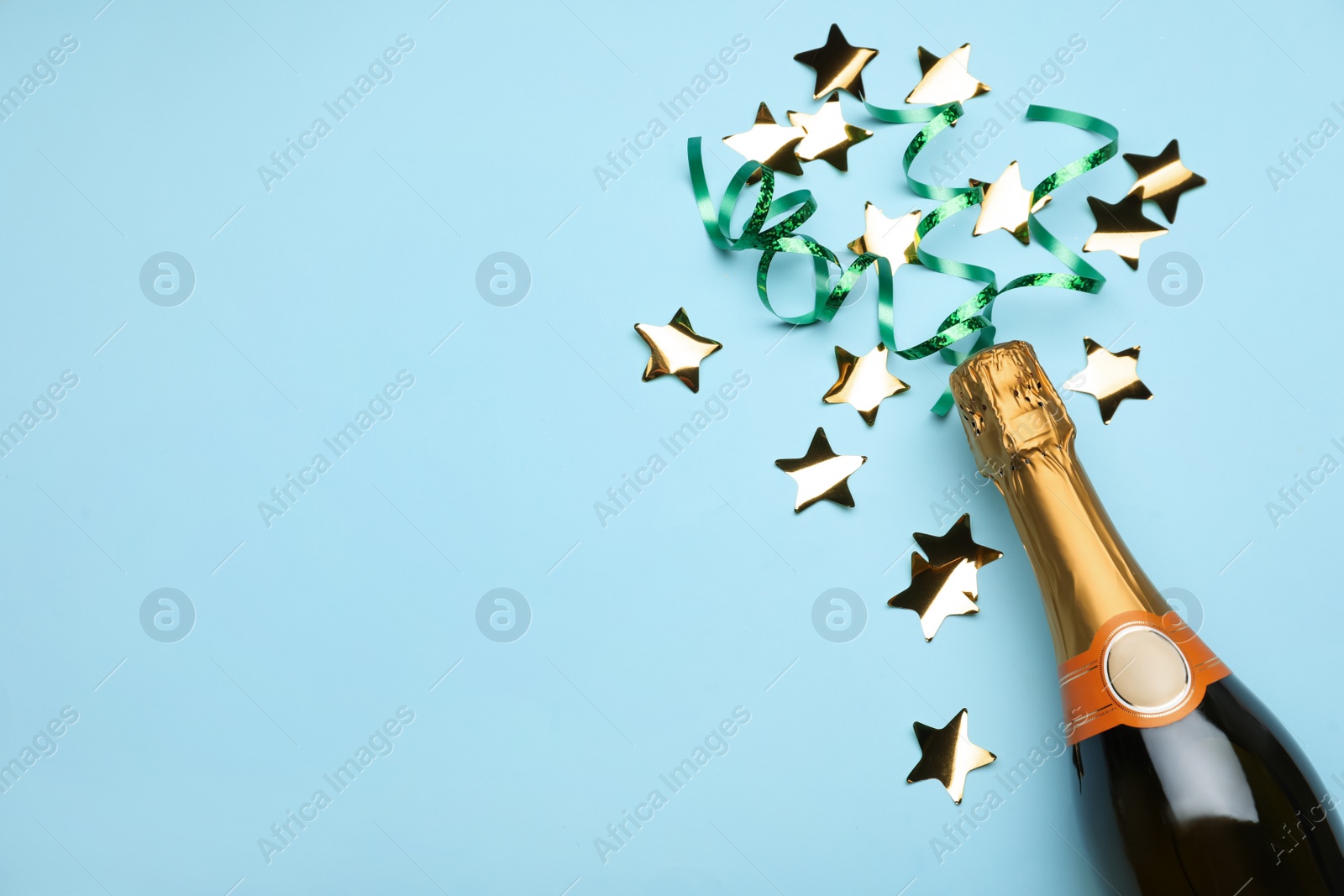 Photo of Flat lay composition with confetti and bottle of champagne on light blue background. Space for text