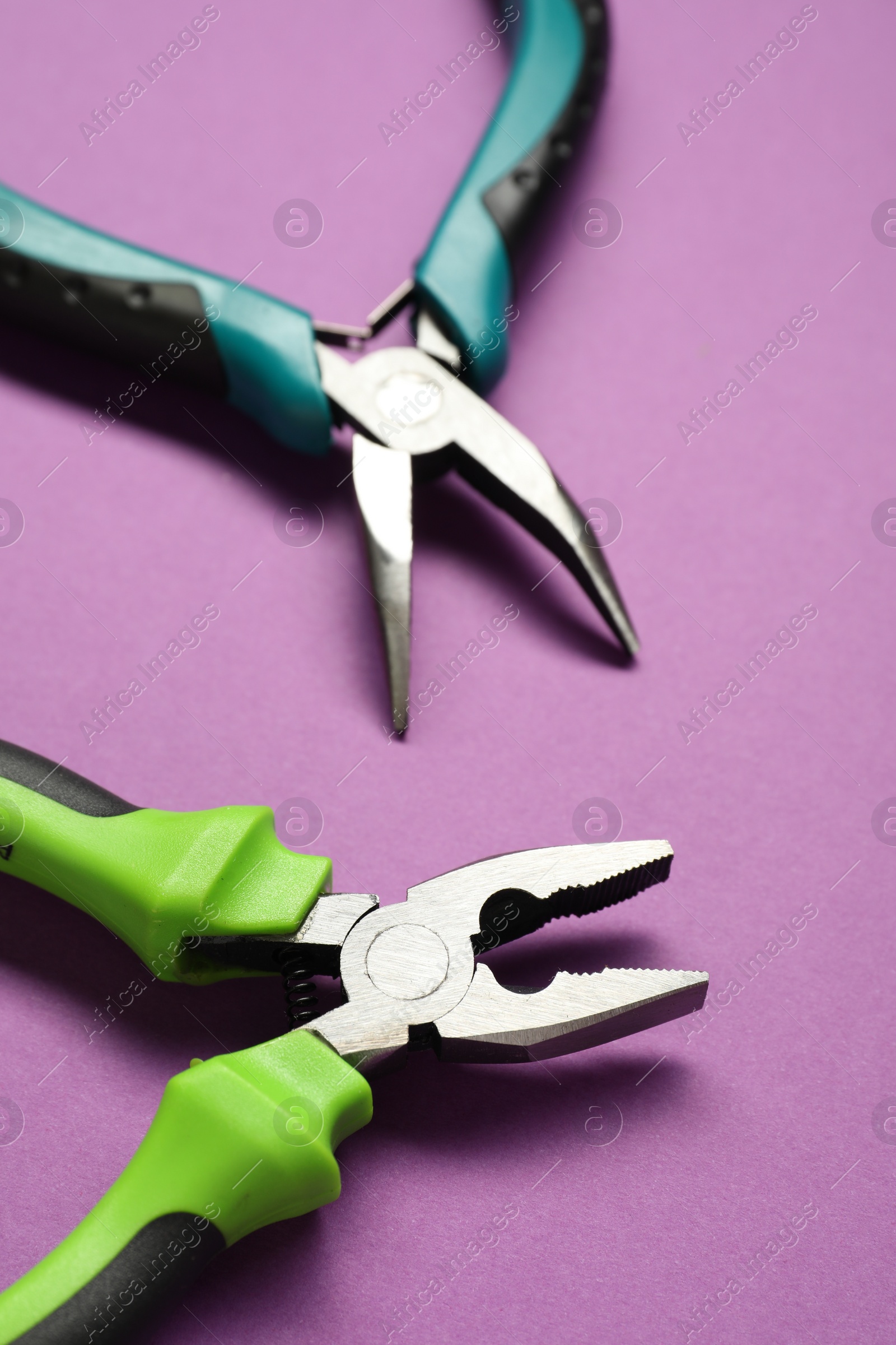 Photo of Two pliers on purple background, closeup view