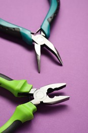 Two pliers on purple background, closeup view