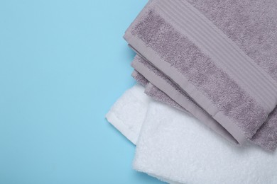 Photo of Different terry towels on light blue background, flat lay. Space for text