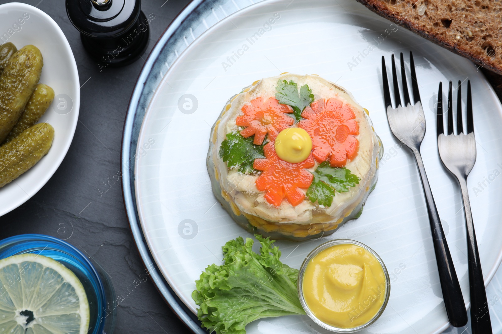 Photo of Delicious chicken aspic served on black table, flat lay