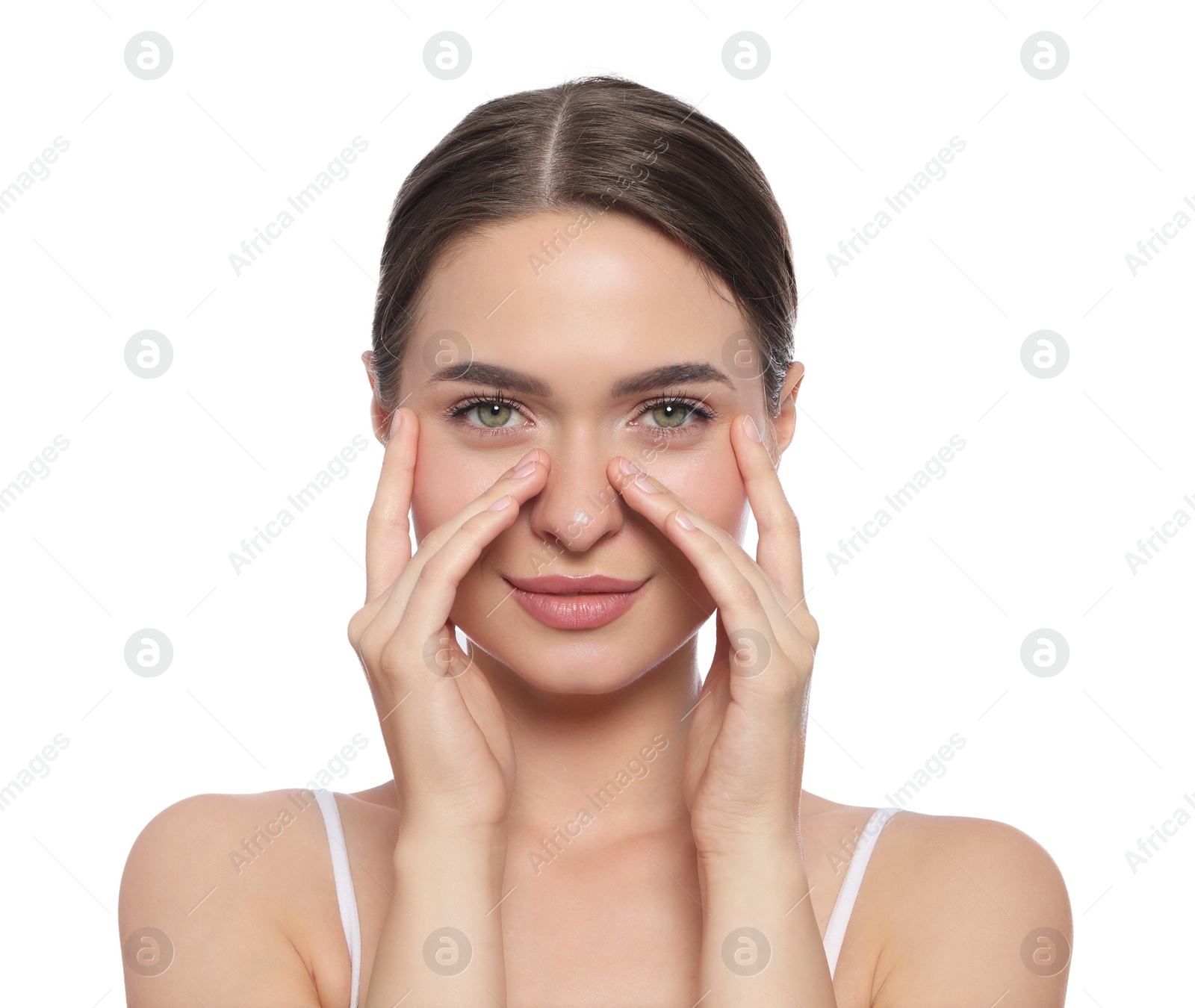 Photo of Young woman applying cream under eye on white background