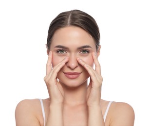 Young woman applying cream under eye on white background