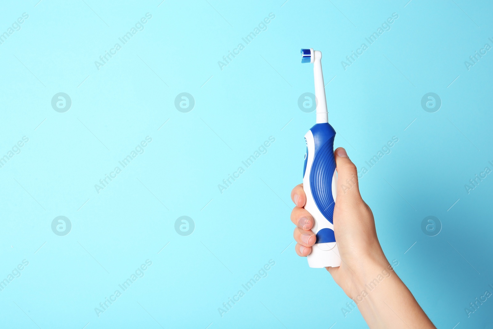 Photo of Woman holding electric toothbrush against color background