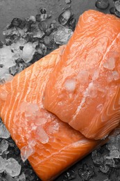 Fresh raw salmon with ice on black table, flat lay