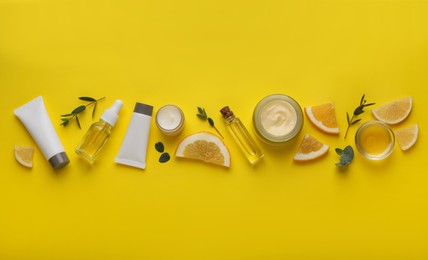 Photo of Body cream and other cosmetic products with ingredients on yellow background, flat lay