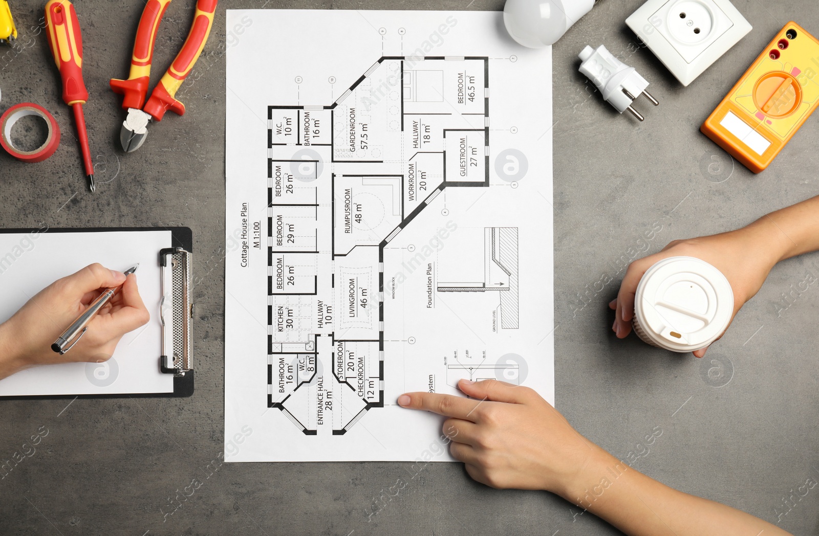 Photo of Electrician discussing house plan with client on gray table, top view