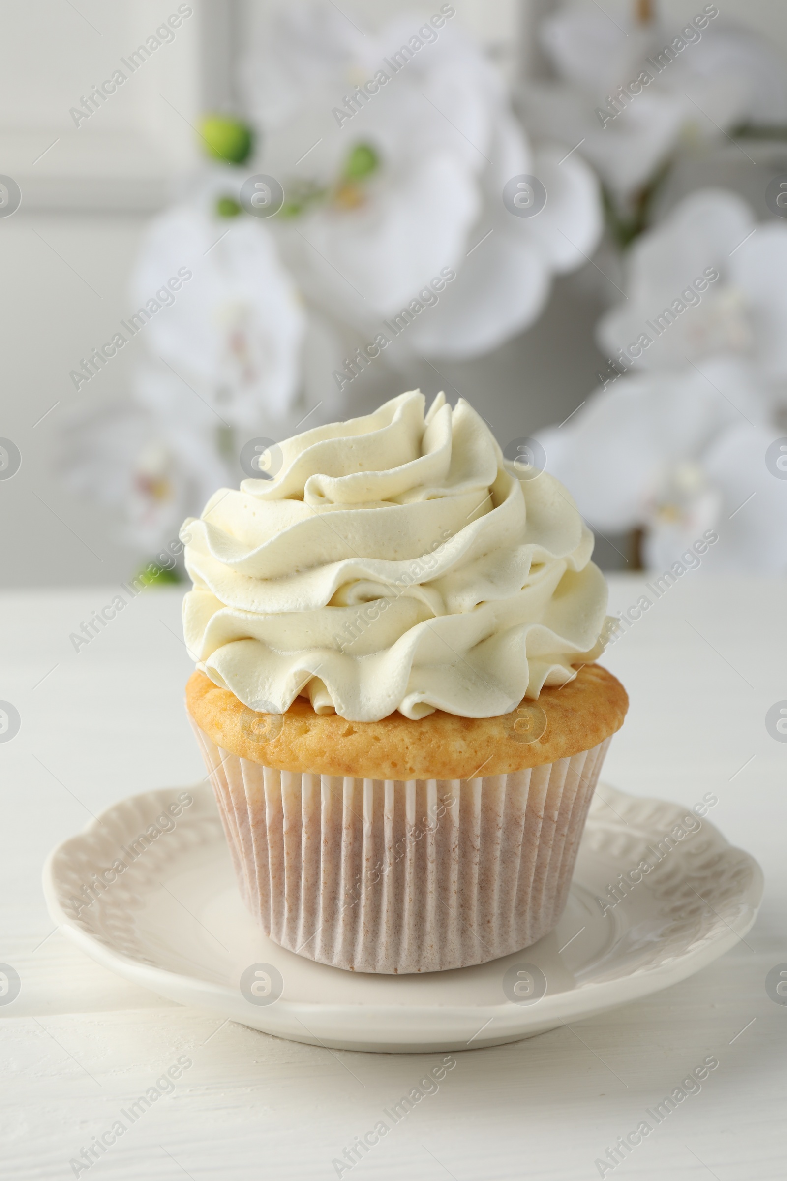 Photo of Tasty vanilla cupcake with cream on white table, closeup