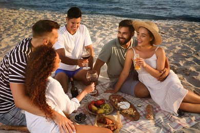 Photo of Group of friends having picnic on sandy beach near sea