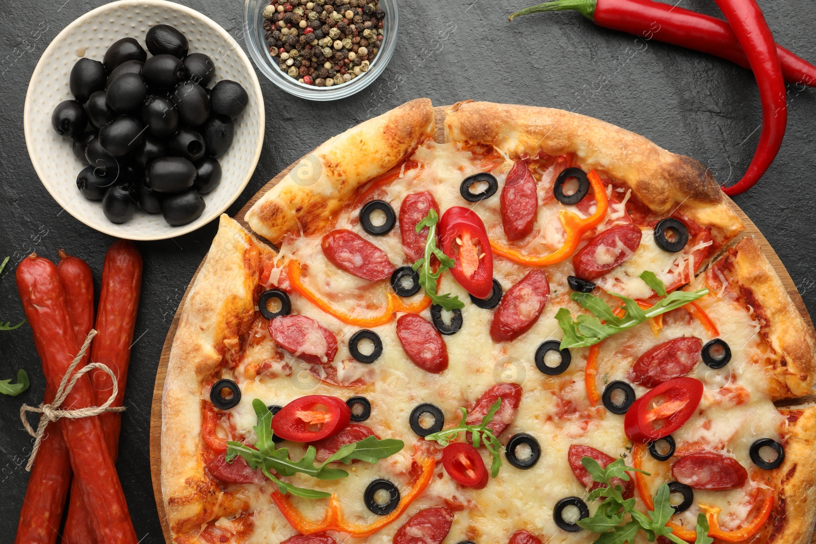 Photo of Tasty pizza and ingredients on black table, top view