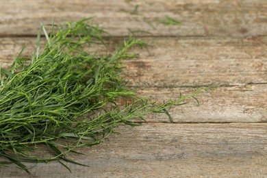 Photo of Bunch of fresh tarragon on wooden table. Space for text