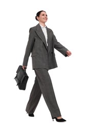 Beautiful businesswoman in suit with briefcase walking on white background