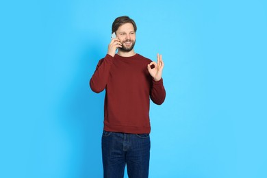 Man talking on smartphone against light blue background