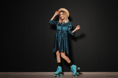 Photo of Young woman with retro roller skates against black wall